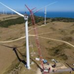 Crawler crane lifting wind turbine components in wind farm construction project